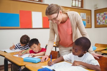 Pretty teacher helping pupil in classroom