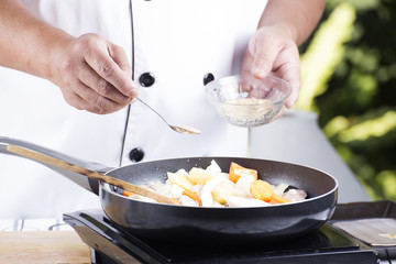 Chef putting the seasoning to the pan for cooking