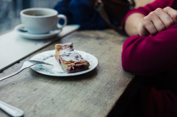 Woman having cake by window in cafe