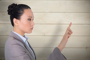 Composite image of unsmiling asian businesswoman pointing