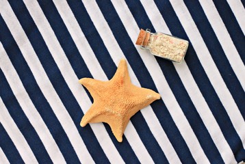 Starfish and bottle with sand on stripy marine style background