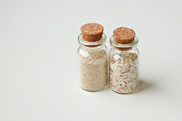 corked bottles with sea sand on white