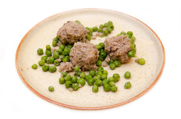 Meatballs with peas on plate on white background