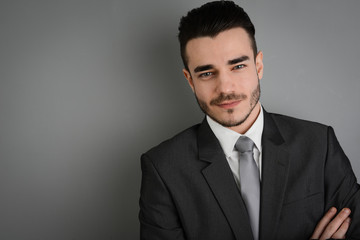 portrait of a young business man posing in front of gray wall
