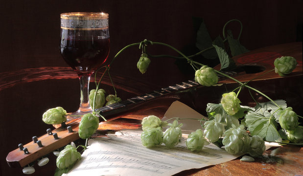 Red wine in a transparent glass and a branch of hop and a mandol