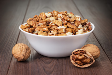 walnuts in the white bowl on wooden table