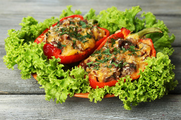 Stuffed red peppers with greens on plate on wooden table