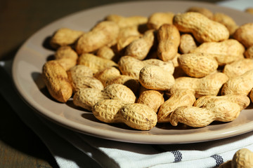 Peanuts on plate, on wooden background