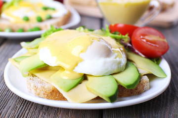 Fototapeta na wymiar Toast with egg Benedict and avocado on plate on wooden table