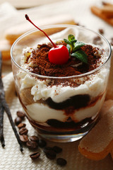 Tasty tiramisu dessert in glass, on napkin, on wooden