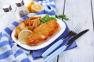 Breaded fried fish fillet and potatoes with asparagus and