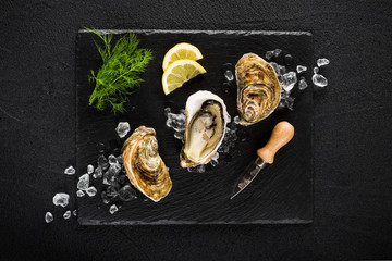 Fresh oysters on a black stone plate top view - 78336767