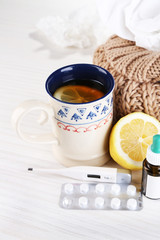 Hot tea for colds, pills and handkerchiefs on table close-up