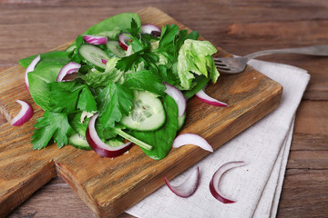 Mix salad leaves with sliced cucumber and onion