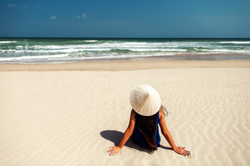 Fototapeta na wymiar girl on the beach with vietnamese hat