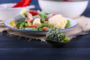 Frozen vegetables on plate on napkin, on wooden table