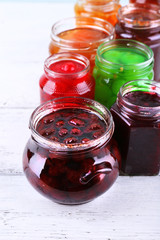 Homemade jars of fruits jam on color wooden planks background