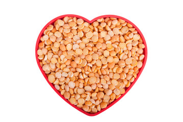 Peas in a dish in the shape of a heart on a white background.