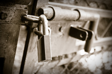 Metal gate closed with padlock - sepia toned