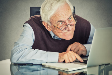 Elderly old man using laptop computer sitting at table