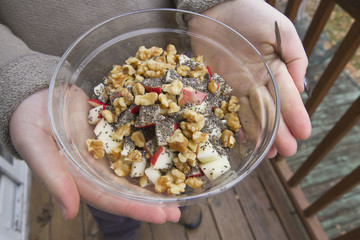 Hands Holding a Glass Bowl of Apples, Walnuts, and Chia Seeds