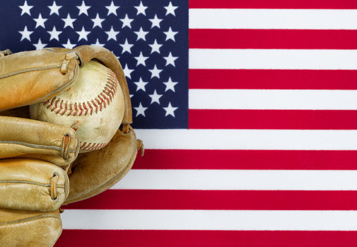 Worn baseball glove and ball on American Flag