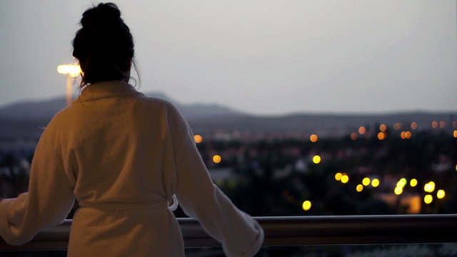 Woman in bathrobe stretching and enjoying view from terrace 