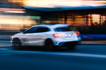Fototapeta na wymiar White SUV Car in a Blurred City Scene