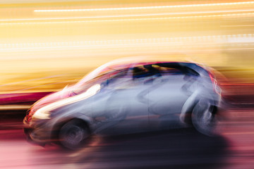Fototapeta na wymiar Grey Compact Car in a Blurred City Scene