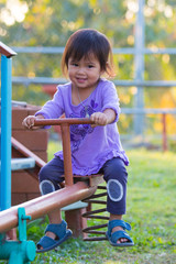 Happy little girl is riding on see-saw on playground