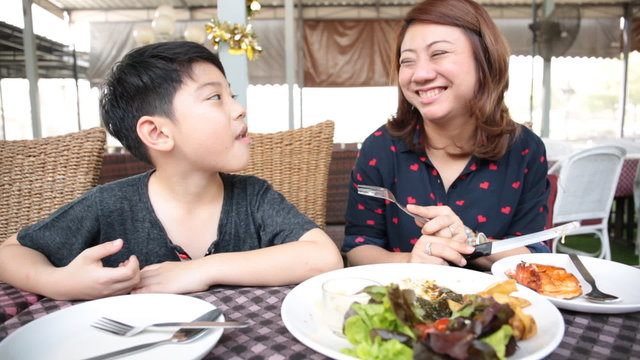 Asian mother with son eating lunch at home
