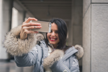 Beautiful young brunette taking a selfie in the city streets