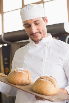 Baker showing tray of fresh bread