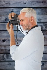 Composite image of smiling man taking a photo on digital camera
