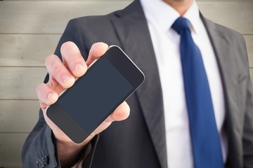 Composite image of businessman showing his smartphone screen