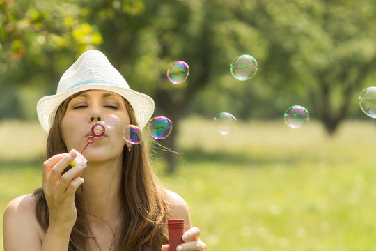 Young pretty woman have fun with bubble in summer park