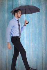 Composite image of focused businessman under umbrella stepping