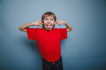 European-looking boy of ten years shows tongue, pulling the ears