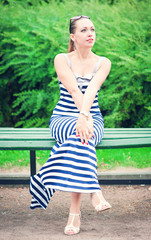 Naklejka premium Young beautiful fashionable woman wearing striped dress sitting
