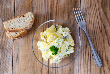 Kartoffelsalat in einer Glasschale auf Holz