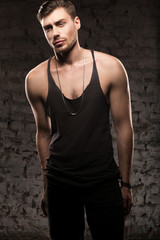 handsome muscular man in a black t-shirt standing near the wall
