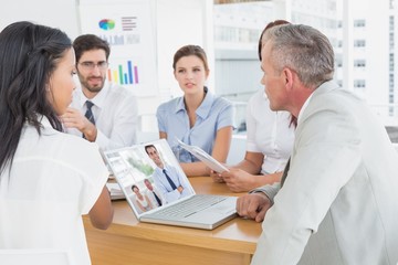 Cheerful businessman posing while his colleagues are working