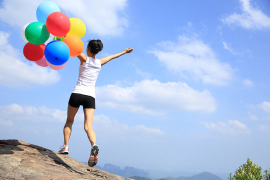 young asian woman mountain peak with colored balloons 
