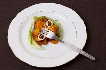 Portion of pork stew with potatoes, cheese, cauliflower leaves.