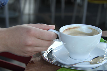 Young woman drinking coffee in a cafe outdoors