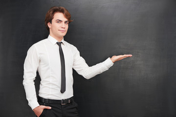 Young man pointing at blank chalkboard