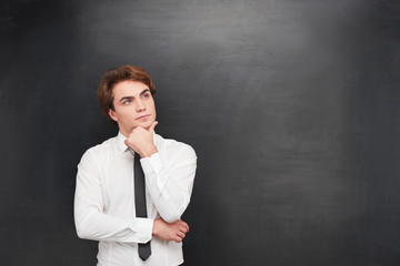 Thoughtful young man on chalkboard background