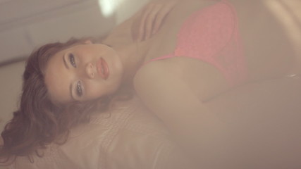 Sexy brunette lying on a bed in  cozy room