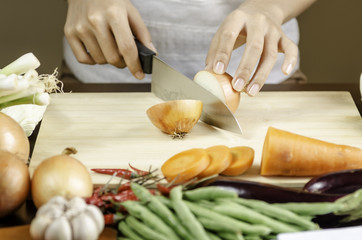 image of a woman cutting onion with vegetables around her