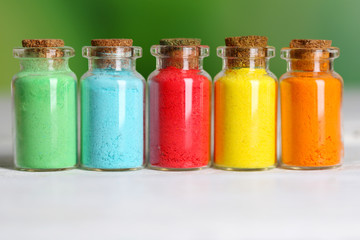 Bottles with colorful dry pigments on wooden background